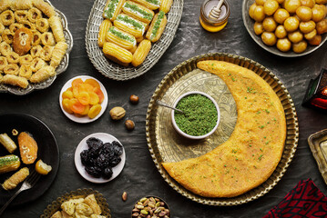 Arabic Cuisine: Middle Eastern desserts. Delicious collection of Ramadan traditional desserts. Served with tasty nuts, dried fruits, honey syrup and oriental tea. Top view with close up.