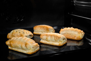 Five buns with ham and cheese baking and rising on tray in electric oven. Homemade bakery, food, cooking and pastry concept
