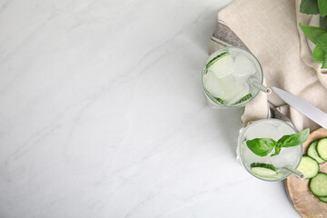 Tasty fresh cucumber water with basil on white marble table, flat lay. Space for text