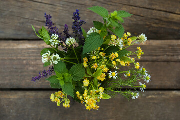Bouquet of different fresh herbs on wooden table, top view