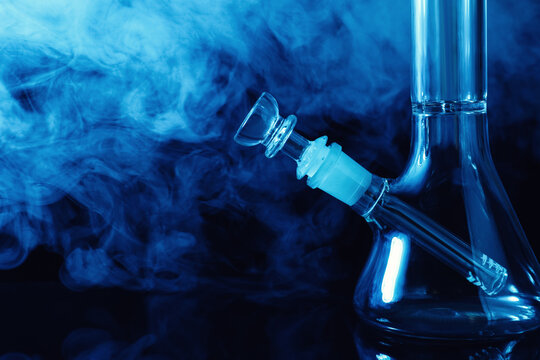 Closeup view of glass bong with smoke on black background, space for text. Smoking device