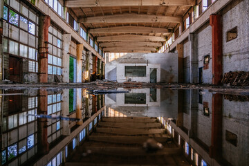 Inside of flooded dirty abandoned ruined industrial building with water reflection