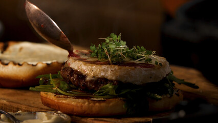 Male chef preparing burger at the restaurant kitchen. Stock footage. Close up of male hands adding wine and cranberry sauce to the tasty delicious beef burger, foodporn.