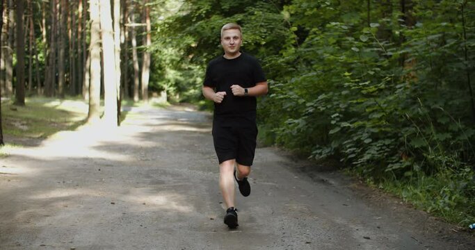 Healthy running runner man workout on road. Jogging male fitness model working out training for marathon on forest road in amazing nature landscape. High quality 4k footage