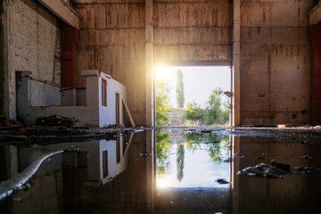 Inside of flooded dirty abandoned ruined industrial building with water reflection