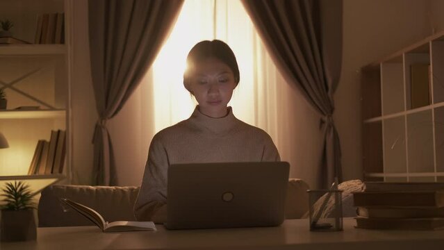 Home learning. Online education. Remote study. Smart girl watching video class using laptop taking notes at cozy living room workplace interior.
