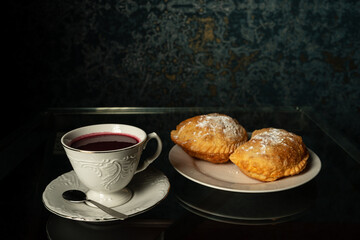 fried empanadas with cheese next to cup with purple api, purple corn drink