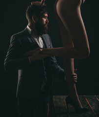 Fetish legs. Fashion portrait of attractive young man with womans sexy legs. - obrazy, fototapety, plakaty