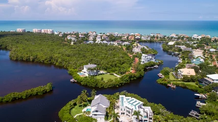 Foto op Plexiglas Aerial Drone Perspective of Real Estate in Bonita Springs, Florida with the Bay and a Preserve in the Foreground and the Gulf of Mexico in the Background Featuring a Blue Sky and Blue Water © Ray Dukin