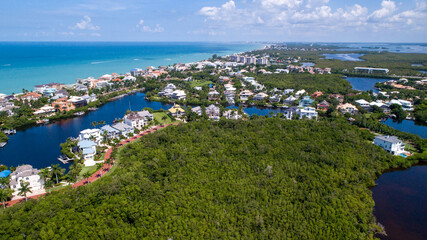 Fototapeta na wymiar Aerial Drone View of Beachside Community in Naples, Florida with the Gulf of Mexico to the Left and Blue Bay Water to the right with Mangroves