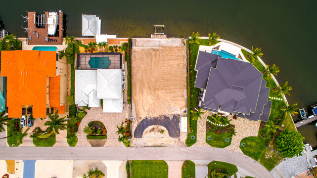 Aerial Drone View of a Cleared Lot Ready for Construction in Naples, Florida with Waterfront Homes to the Left and Right
