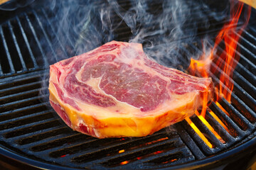 Barbecue dry aged Wagyu cote de boeuf steak grilled as close-up on a charcoal grill with fire and smoke