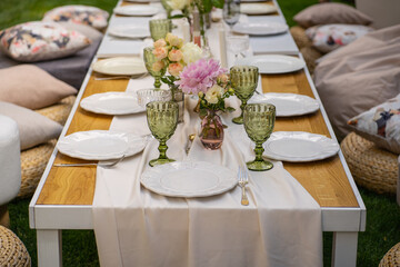 Holiday. Festive decoration. Table serving. Beautiful flower compositions. Green grass lawn. Summer pleasant meetings.