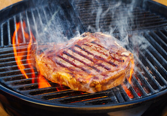 Barbecue dry aged Wagyu cote de boeuf steak grilled as close-up on a charcoal grill with fire and smoke