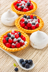 Meringue cookies and tarts with berries  on the table