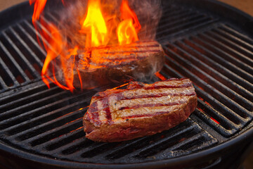BBQ dry aged wagyu roast beef steak grilled as close-up on a charcoal grill with fire and smoke