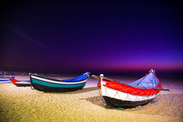 Nazare, Portugal: Night photography of traditional colorful fishing boats docked on the sandy beach