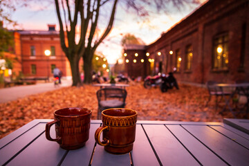 Lodz, Poland: A cup of hot drink on the table in the Ksiezy Mlyn historic distric during .autumn evening - obrazy, fototapety, plakaty