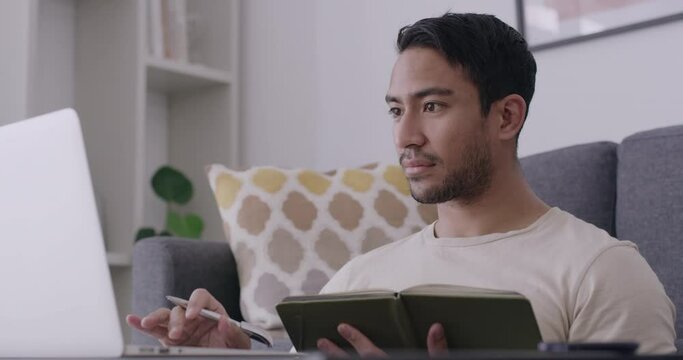 Studying with distance learning and education. Young man taking an online course on a laptop at home. Freelancer writing notes and browsing online to do research and planning while working remotely.