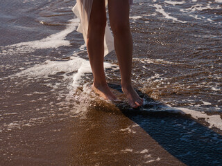 sea waves and feet of a walking woman