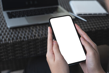 Cell phone blank white screen mockup. Woman hands holding, using mobile phone at coffee shop, template for advertisement