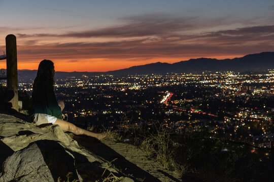 A lone female watches the sun set over the valley in Los Angeles