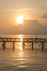 Fototapeta na wymiar Silhouette of man fishing on jetty on mabul island in borneo