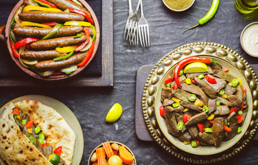 Arabic cuisine; Egyptian Traditional sausage and liver dishes. Served with fresh pita bread, pickles, tahini sauce and lemon. Top view with close up.