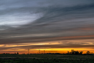 The silhouette of multiple modern windmills on the low horizon in a colorful sunset, outside of Kiy&uacute;, San Jos&eacute;, Uruguay