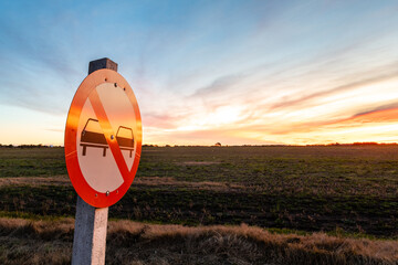 No overtaking sign on the road, under a colorful sunset, on the outskirts of Kiyú, San José,...