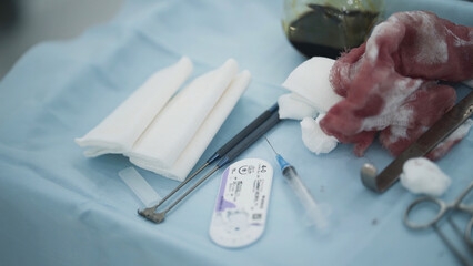 Surgical instruments and bloody bandages. Action. Close-up of surgical table with instruments and...