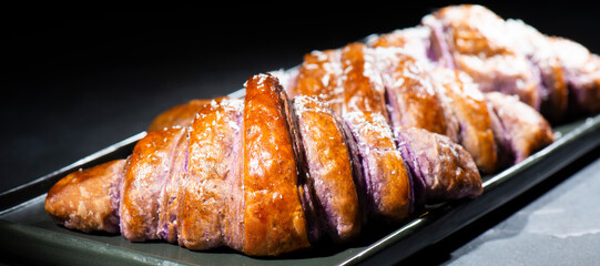 Fresh baked homemade Ube Croissants using flavouring and purple yam powder and three book folds, lightly sprinkled with coconut.