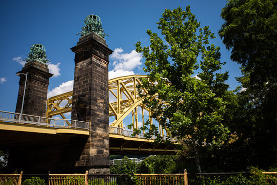 Famous David McCullough Bridge Across The Allegheny River In The Strip District In Pittsburgh, Pennsylvania Seen From Unusual Angle From Below, With Blue Sky And Green Trees. 