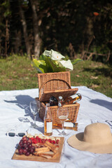 picnic basket with beer and fruits on white sheet