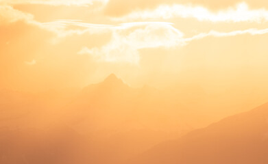 silueta de montañas con nubes anaranjadas del atardecer brillante, hora dorada en montañas	, cielo de atardecer amanecer 