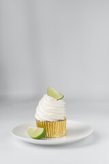 Vanilla cupcake with white buttercream and lime wedge, gold cupcake liners, lime cupcake