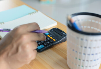 Pension calculation concept, old hands counting finances on a home calculator , close- up