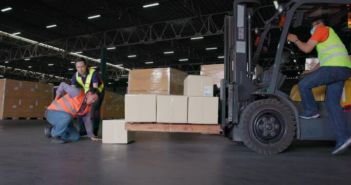 A warehouse is a location where products are stored and distributed. An accident at work causes a warehouse worker to trip and fall while attempting to pick up a cardboard box from the forklift.