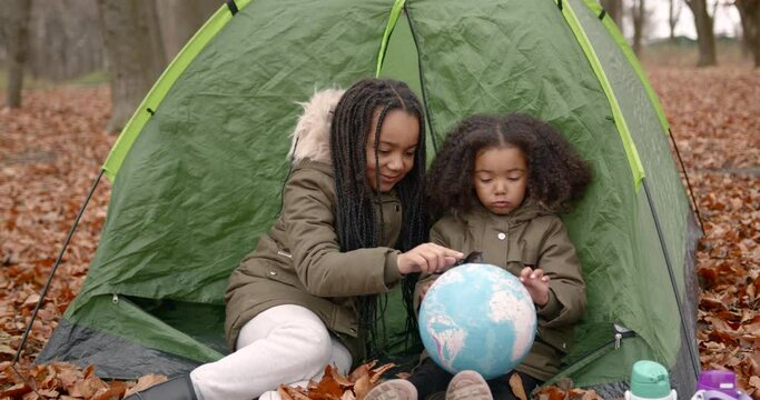 Black race kids holding a globe in an autumn forest