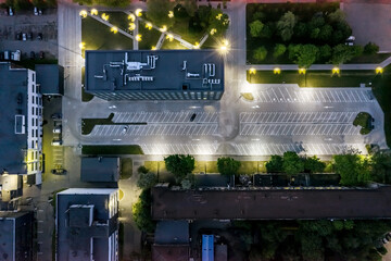 aerial top view of illuminated office building with empty parking lot at night