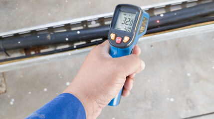 checking the temperature of industrial electrical cables using an infrared thermometer gun,...