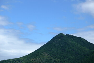 青空と白い雲を背景にした三上山の山頂付近