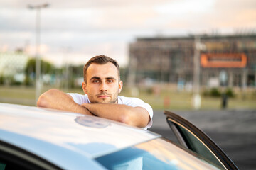 young man poses with his car, proud handsome driver - obrazy, fototapety, plakaty