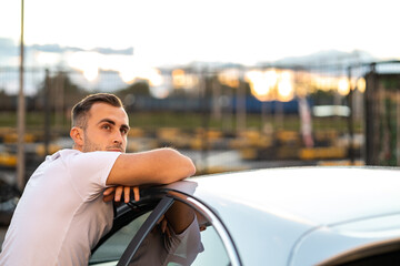 young man poses with his car, proud handsome driver - obrazy, fototapety, plakaty
