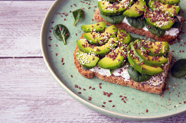 Toast with avocado, cottage cheese, spinach, sesame seeds, flax seeds. Healthy food rich in fiber, trace elements, omega acids, unsaturated lipids.