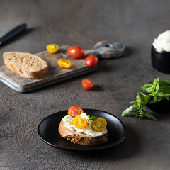 Italian Bruschetta with cream cheese and tomatoe cherry on the black table.Making snack concept