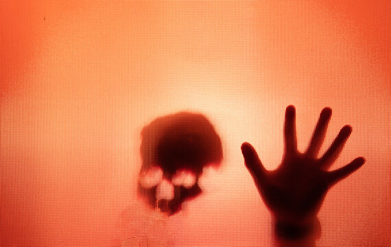 Shadowy figure, skull behind glass - horror background
