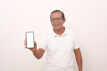 Excited elderly asian man standing while showing his blank cell phone screen. Isolated on white
