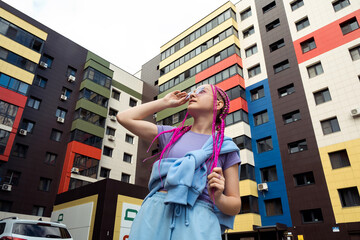 Portrait of a caucasian teenage girl with pink braids against the background of urban high-rise...