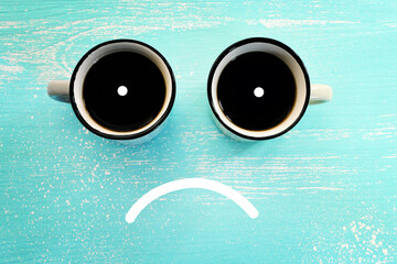Top view image of coffee cup and sad face. Metaphor for sadness or unhappy emotions